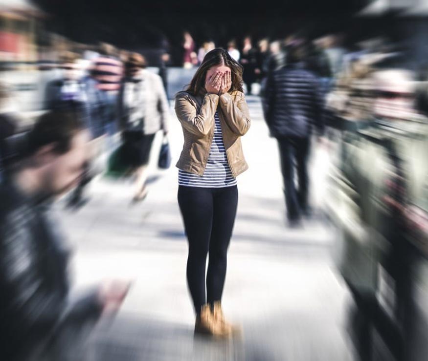 Person covering face in a blurred crowd, emphasizing stress or anxiety.